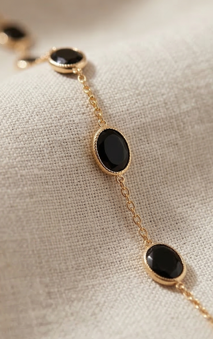 Gold bracelet with onyx black enamel on a beige fabric background